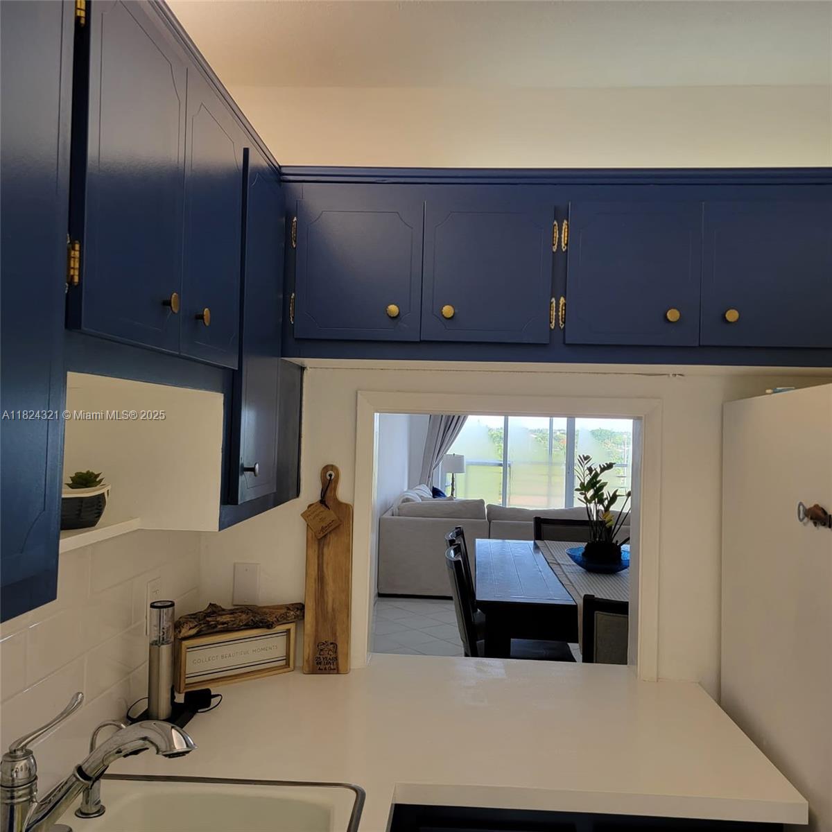 A kitchen features blue cabinets, a white countertop, and a pass-through window to the dining area — 2731 NE 14th St Cswy # 636, Pompano Beach FL 33062, POMPANO BEACH, FL