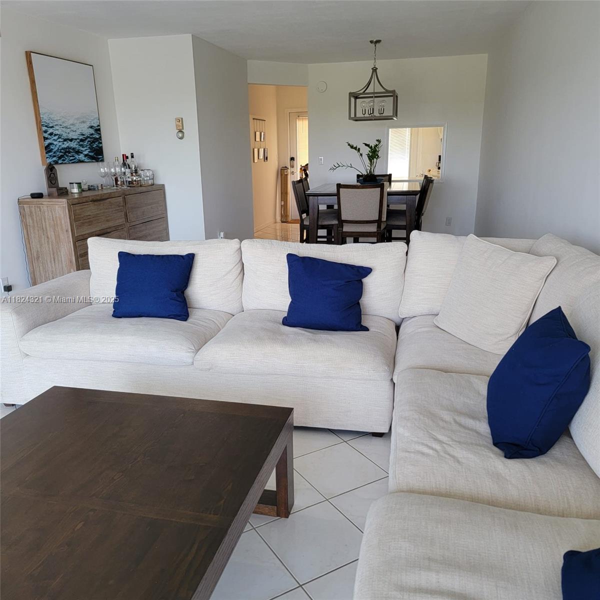 A living room features a large white sectional sofa, a dark wood coffee table, and tile flooring — 2731 NE 14th St Cswy # 636, Pompano Beach FL 33062, POMPANO BEACH, FL