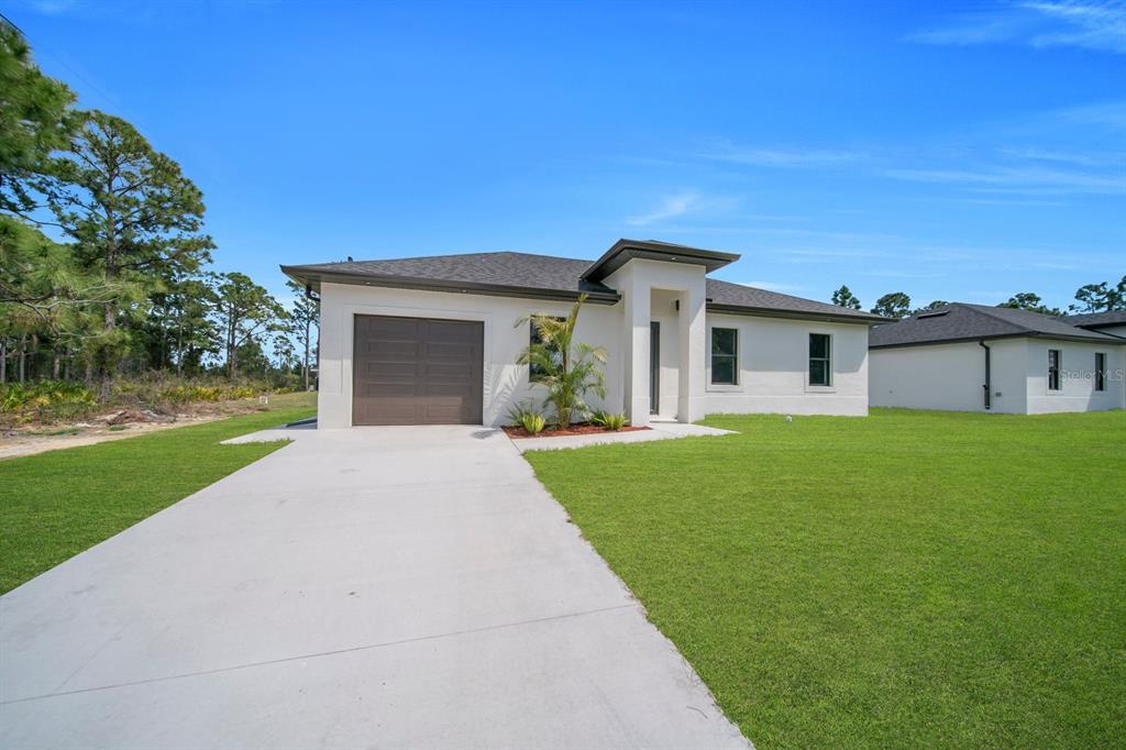 A single-story house with a white stucco exterior, a brown garage door, and a concrete driveway — 635 SUMMIT AVENUE S, LEHIGH ACRES, FL