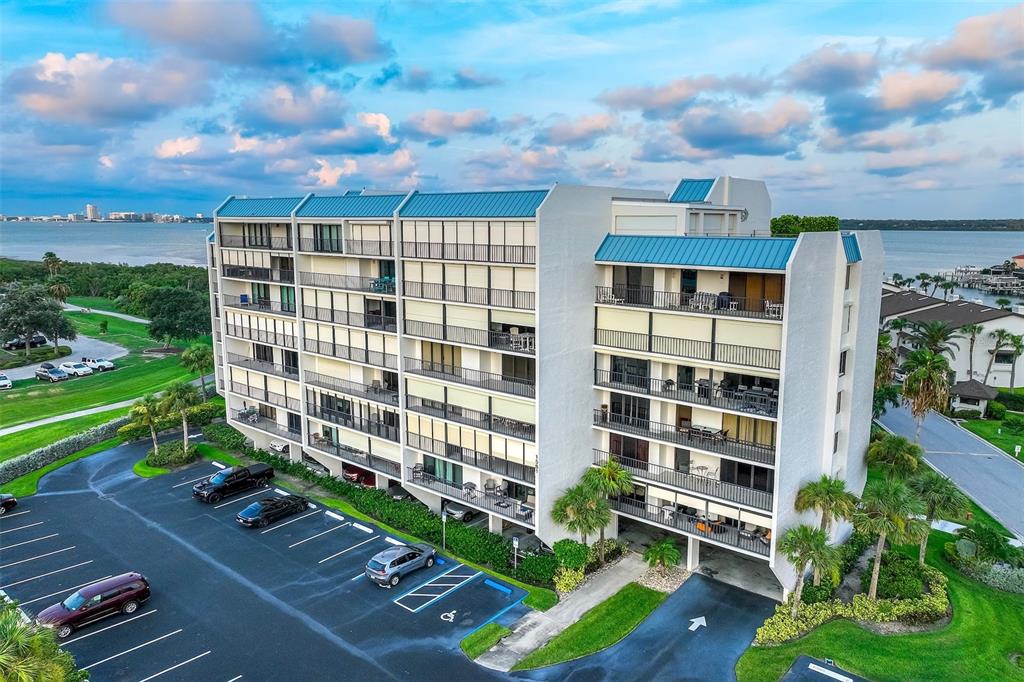 An aerial view shows a multi-story apartment building with balconies and a parking lot — 1581 GULF BOULEVARD UNIT 203N, CLEARWATER BEACH, FL