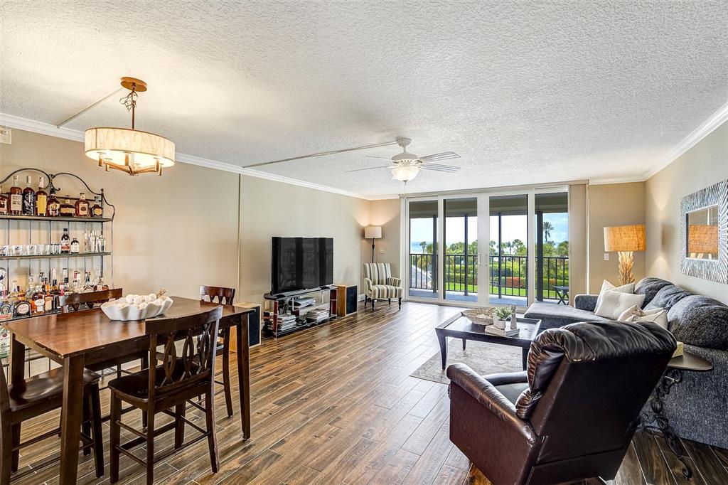 A living and dining area features wood-look flooring, a bar cart, and a balcony view — 1581 GULF BOULEVARD UNIT 203N, CLEARWATER BEACH, FL
