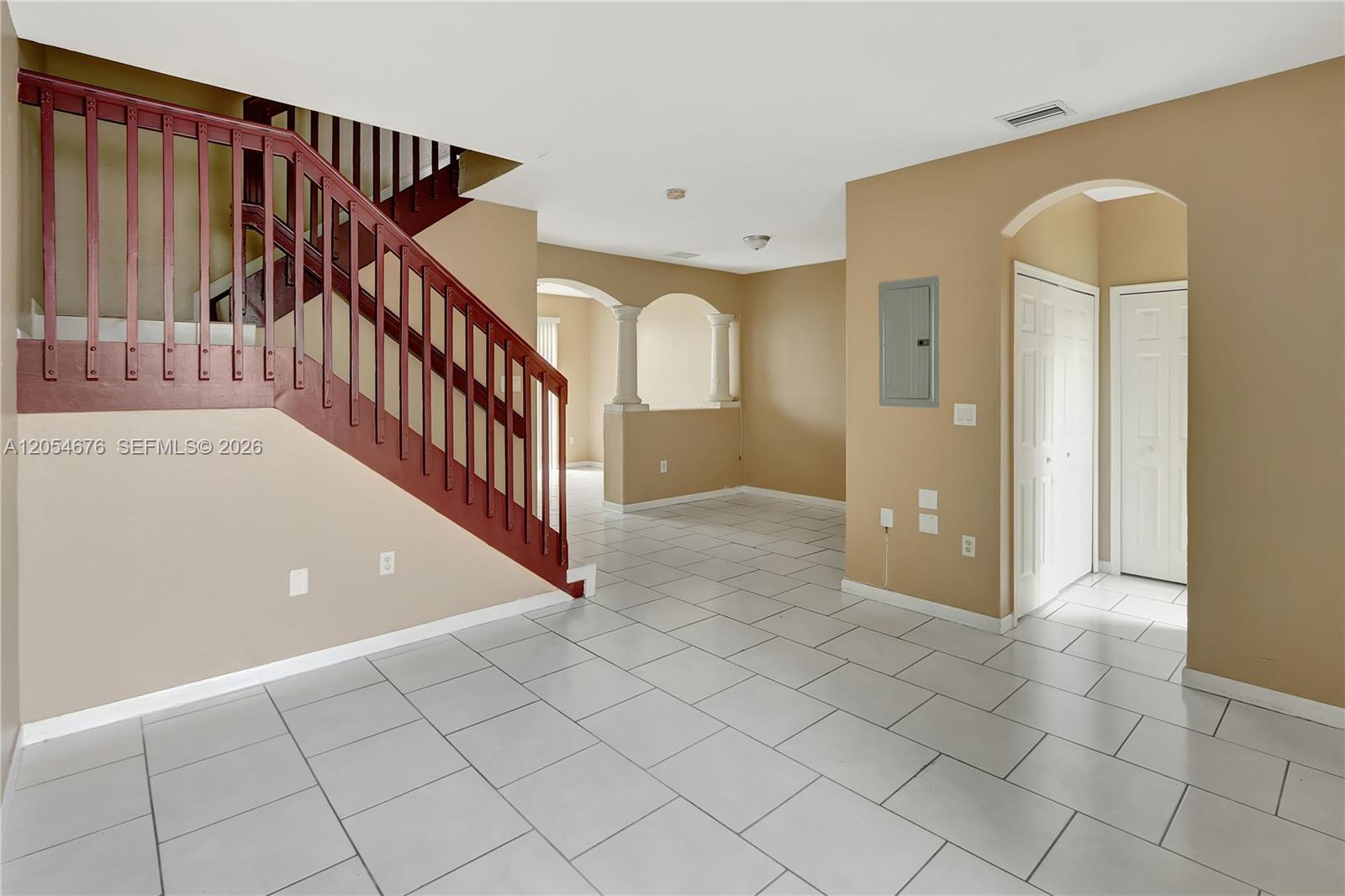 An interior view shows a tiled living area with a wooden staircase and arched openings — 2874 SE 15th Rd # 52, Homestead FL 33035, HOMESTEAD, FL