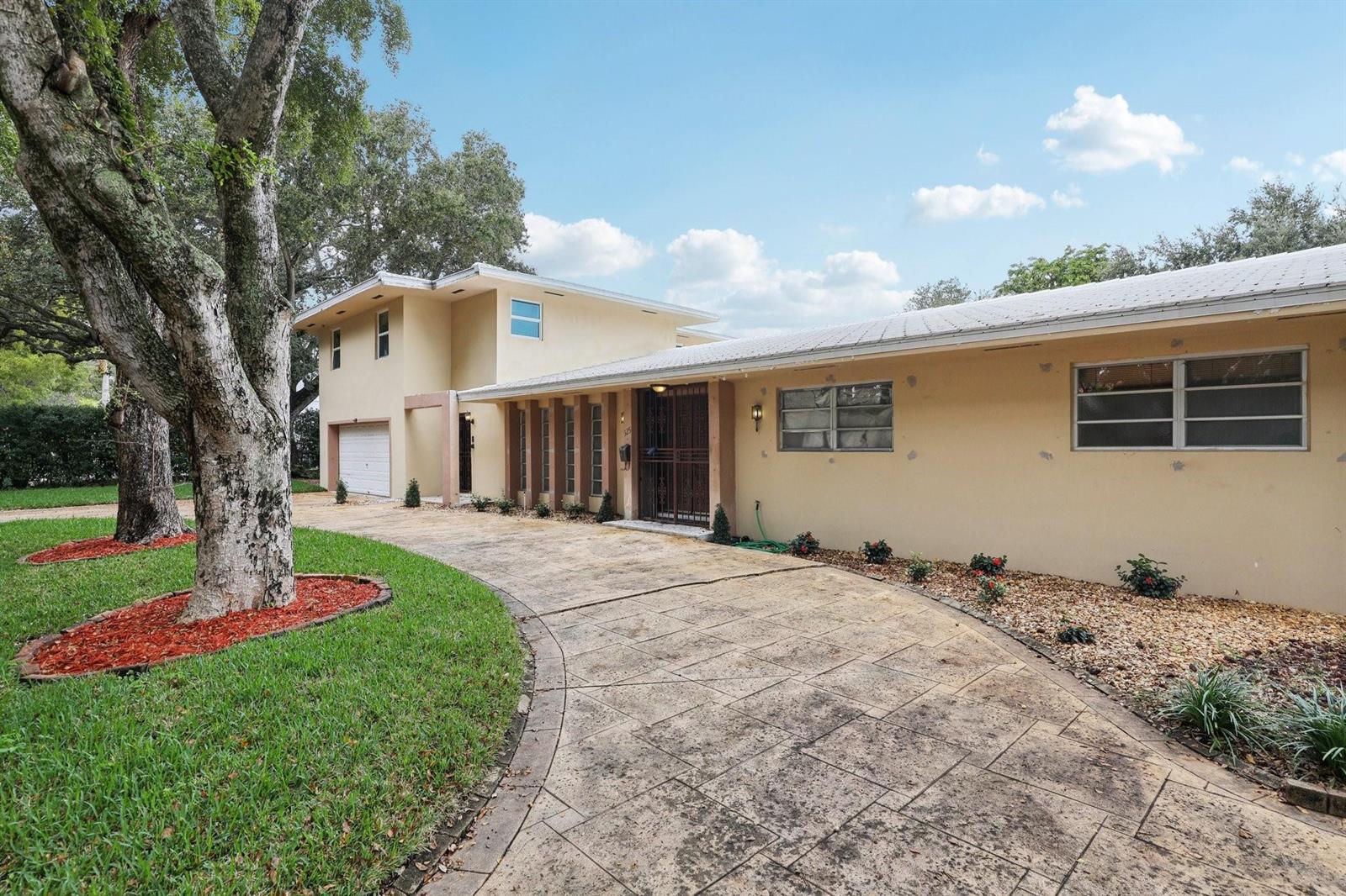 A two-story house with a beige stucco exterior, a metal roof, and a curved driveway — 525 NE 58th Street, Miami FL 33137, MIAMI, FL