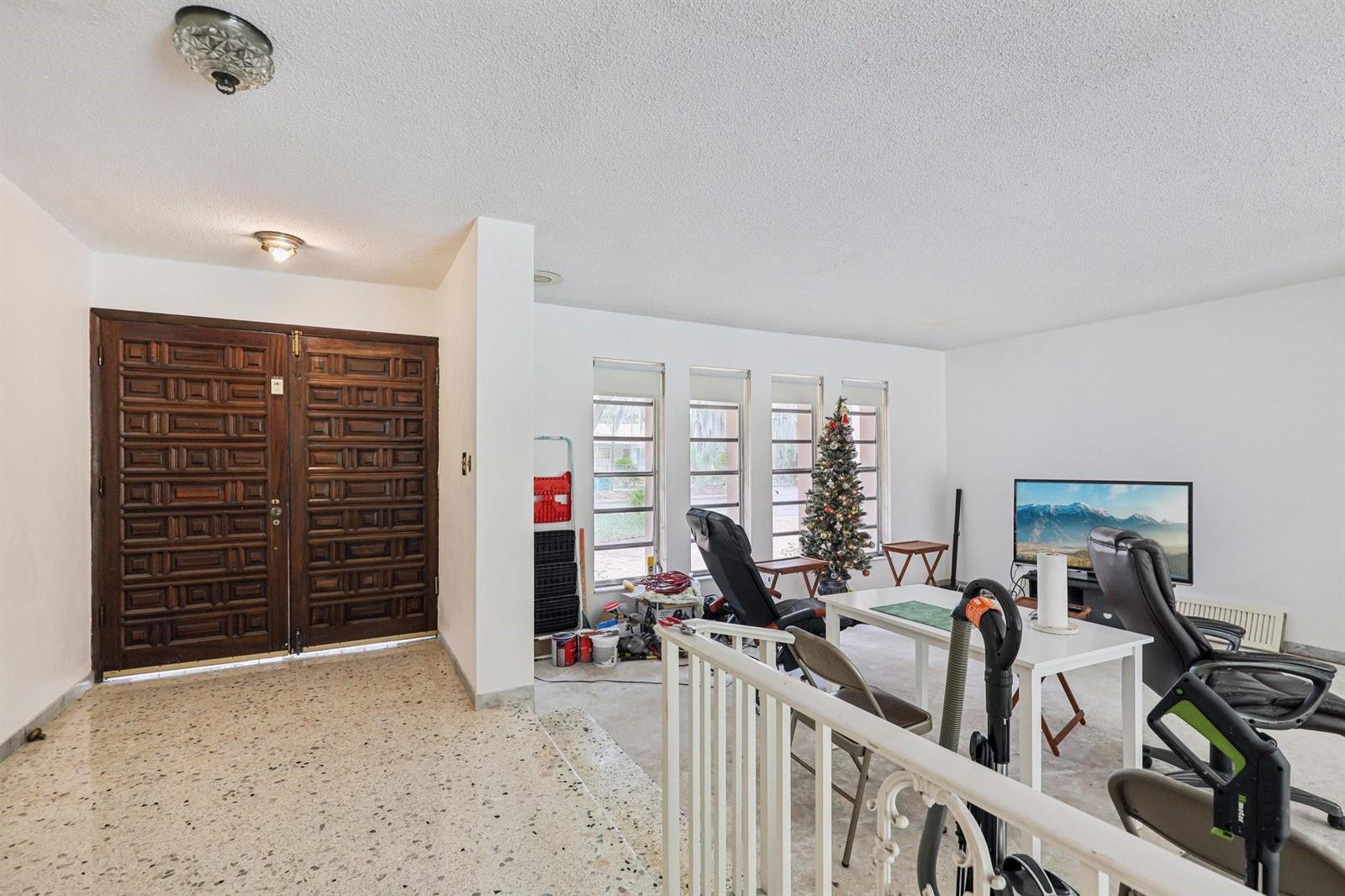 A living room with a terrazzo floor, white walls, and a double wooden front door — 525 NE 58th Street, Miami FL 33137, MIAMI, FL