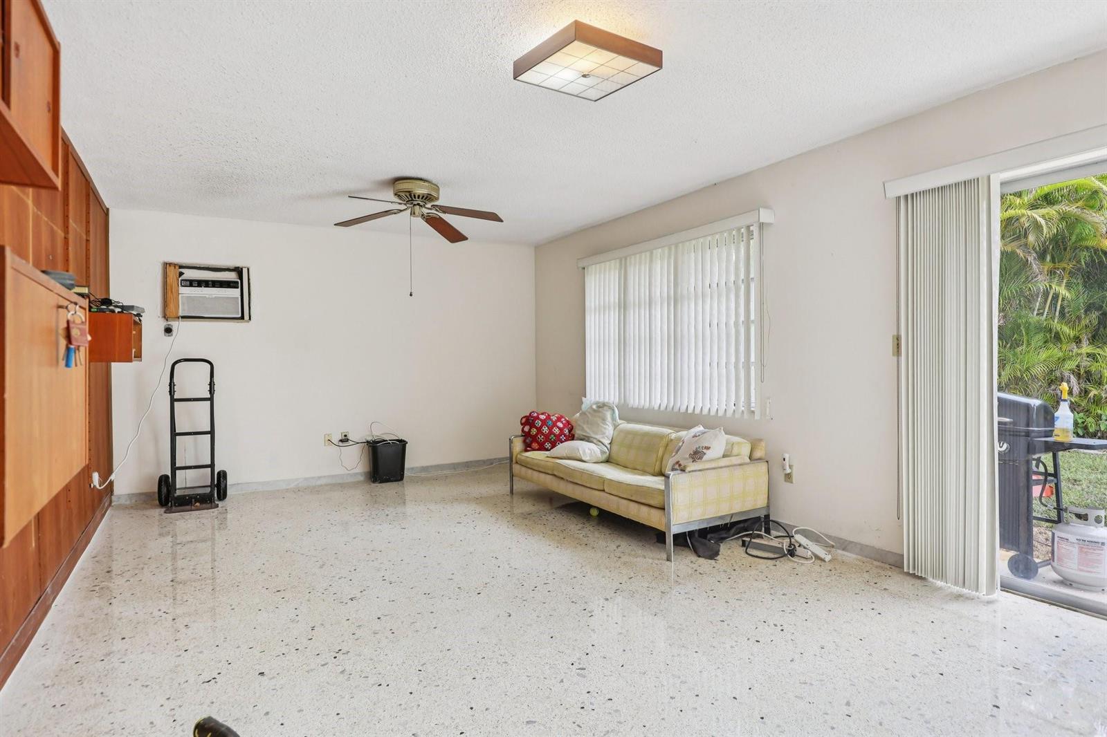 A living room with terrazzo floors, a ceiling fan, a sofa, and sliding glass doors — 525 NE 58th Street, Miami FL 33137, MIAMI, FL