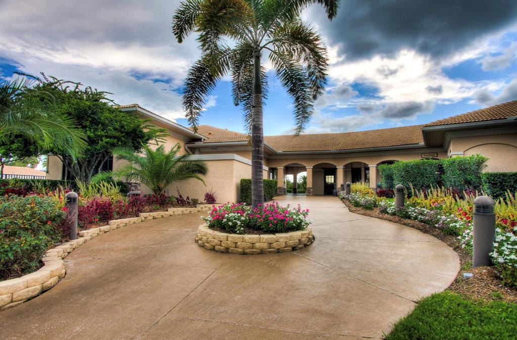 A circular driveway leads to the entrance of a tan building with a palm tree — 5301 MAHOGANY RUN AVENUE UNIT 1023, SARASOTA, FL