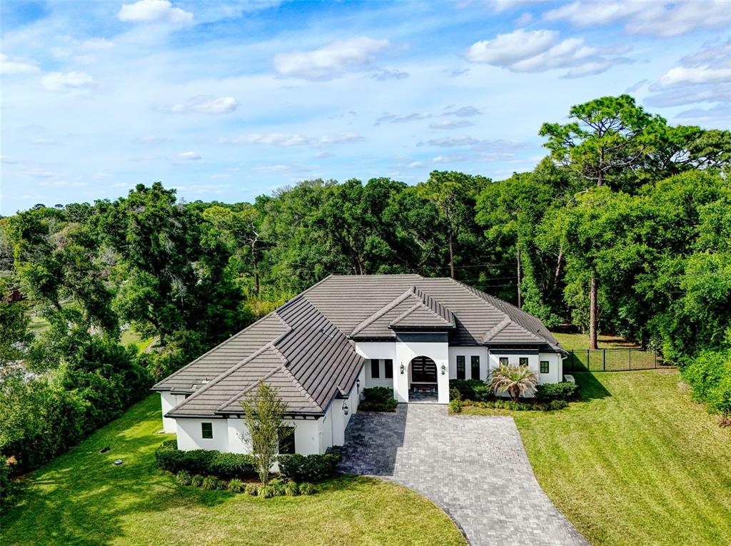 An aerial view of a single-story white house with a dark tiled roof and driveway — 1 STONE GATE S, LONGWOOD, FL