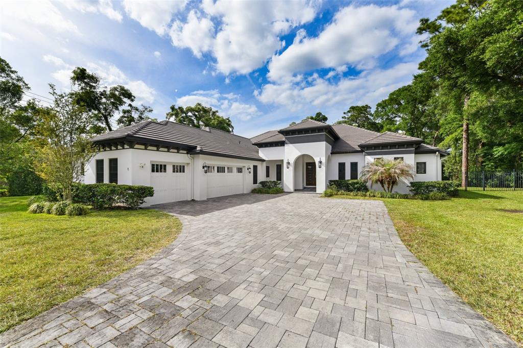 A single-story white house with a paver driveway, three-car garage, and a tiled roof — 1 STONE GATE S, LONGWOOD, FL