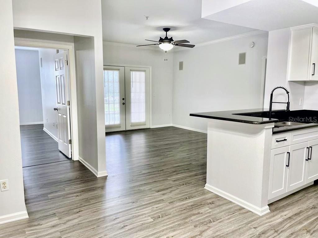 A kitchen with a black countertop and white cabinets overlooks a living area with flooring — 14316 FREDRICKSBURG DRIVE UNIT 514, ORLANDO, FL