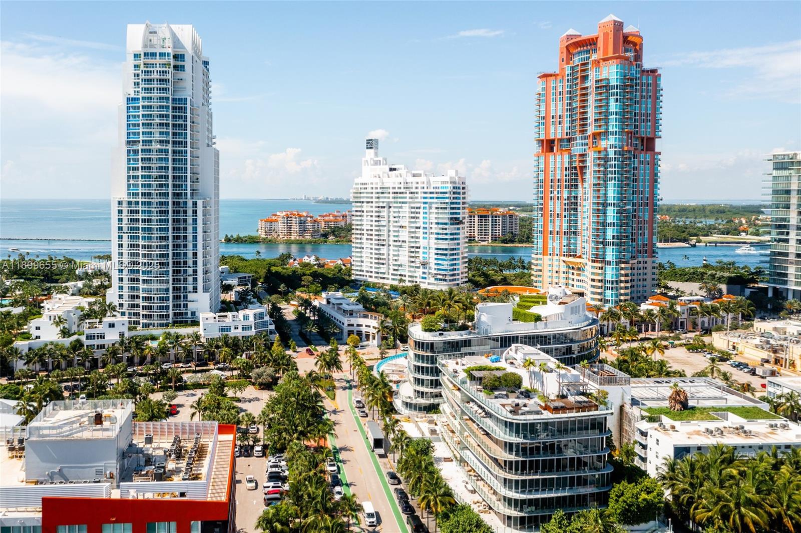 An aerial view of a coastal city featuring high-rise buildings, palm trees, and a waterway — 1 Collins Ave # 207, Miami Beach FL 33139, MIAMI BEACH, FL