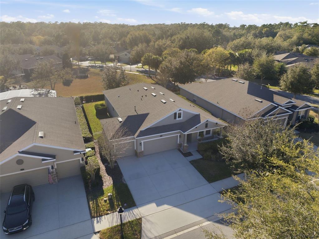 An aerial view shows three suburban houses with driveways and shingled roofs in a neighborhood — 404 W VICTORIA TRAILS BLVD, DELAND, FL