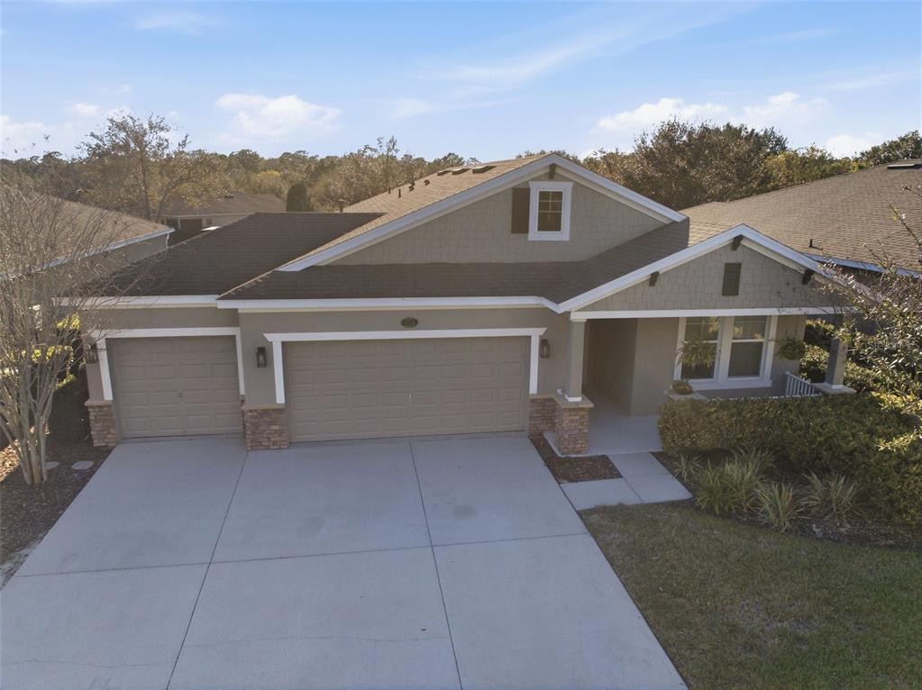 A single-story house with a three-car garage, stone accents, and a concrete driveway — 404 W VICTORIA TRAILS BLVD, DELAND, FL