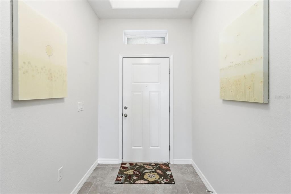 A bright entryway features a white front door, light gray walls, and tiled flooring — 404 W VICTORIA TRAILS BLVD, DELAND, FL