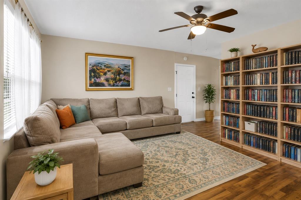 A living room features a sectional sofa, a large area rug, and tall wooden bookshelves — 1733 LARKIN ROAD, SPRING HILL, FL
