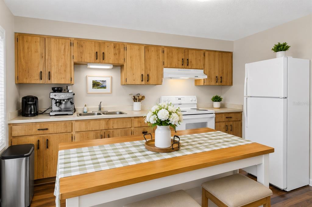 A kitchen features light wood cabinets, white appliances, a dining table, and a stainless refrigerator — 1733 LARKIN ROAD, SPRING HILL, FL