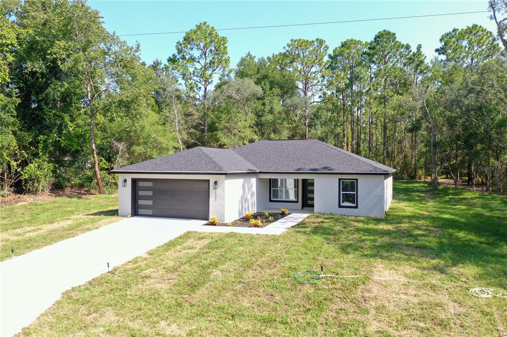 An open-concept kitchen and living area features white cabinetry, a center island, and tile flooring — 22575 SW ANCHOR BOULEVARD, DUNNELLON, FL