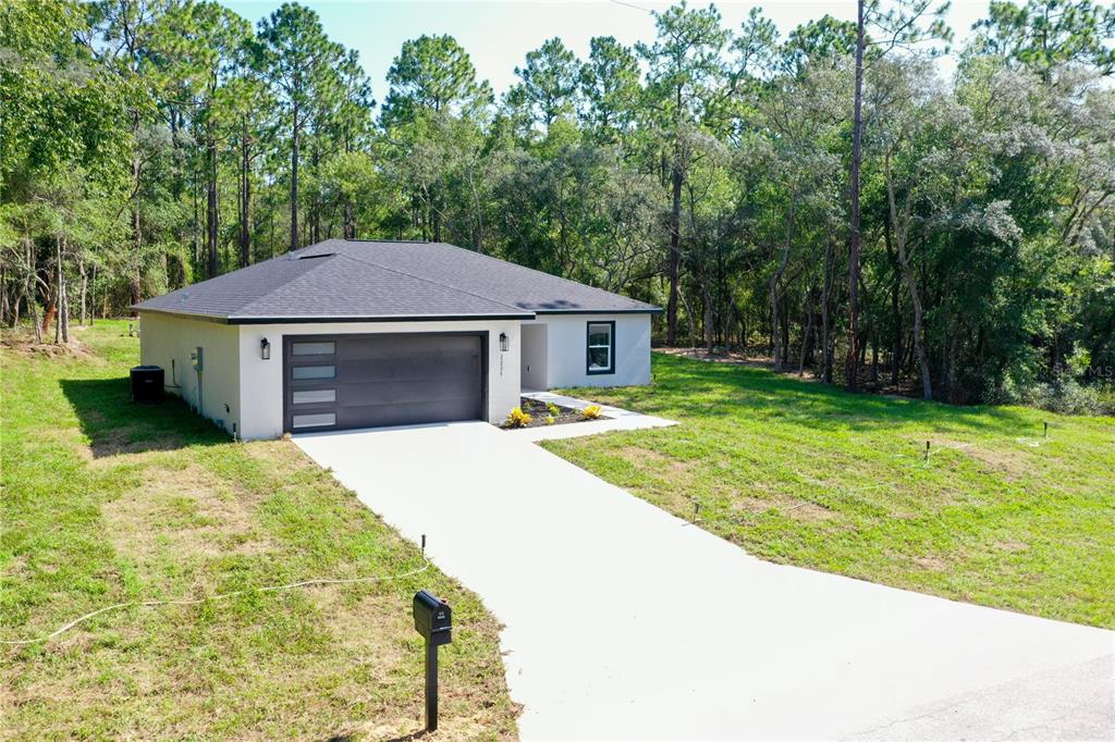 A kitchen with white cabinets and a center island opens to a spacious living area — 22575 SW ANCHOR BOULEVARD, DUNNELLON, FL
