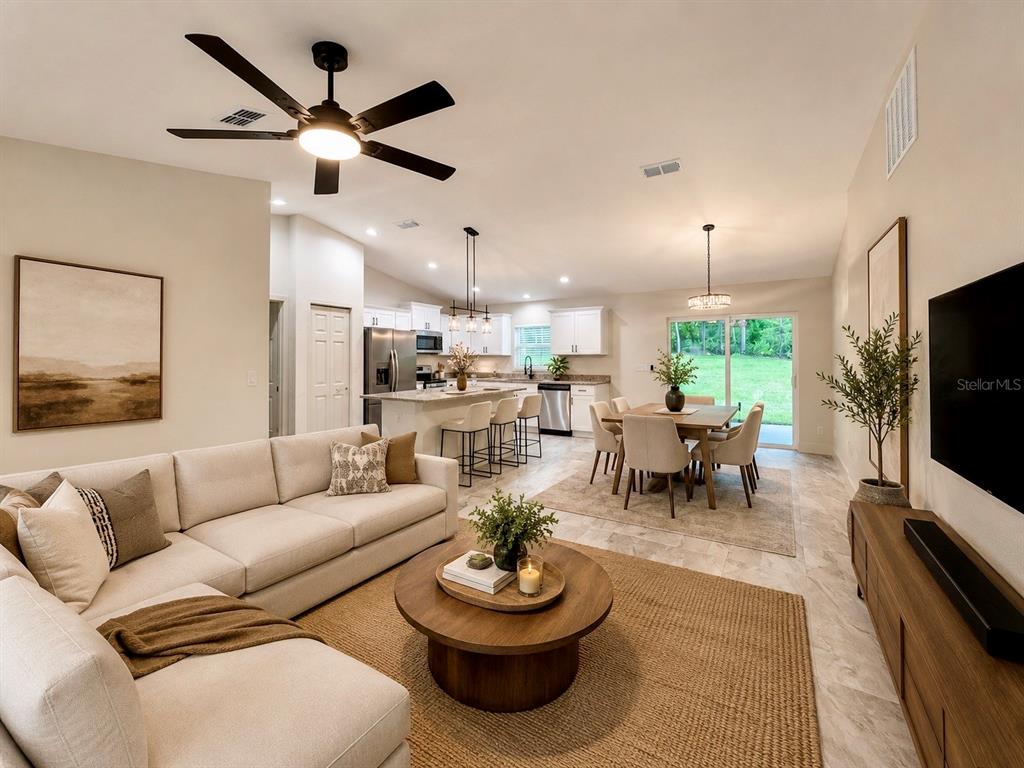 A dining area with a wooden table and chairs sits adjacent to a white kitchen — 22575 SW ANCHOR BOULEVARD, DUNNELLON, FL