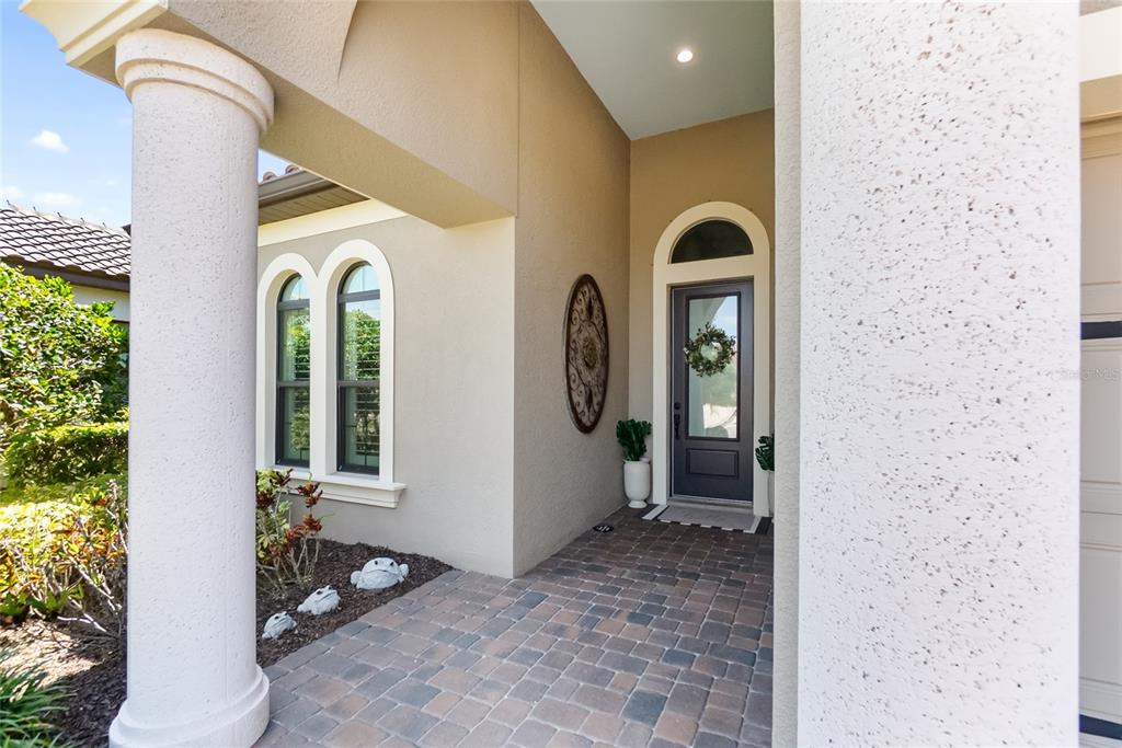 A paved entryway features a dark front door, arched windows, and a large white column — 16512 BERWICK TERRACE, BRADENTON, FL