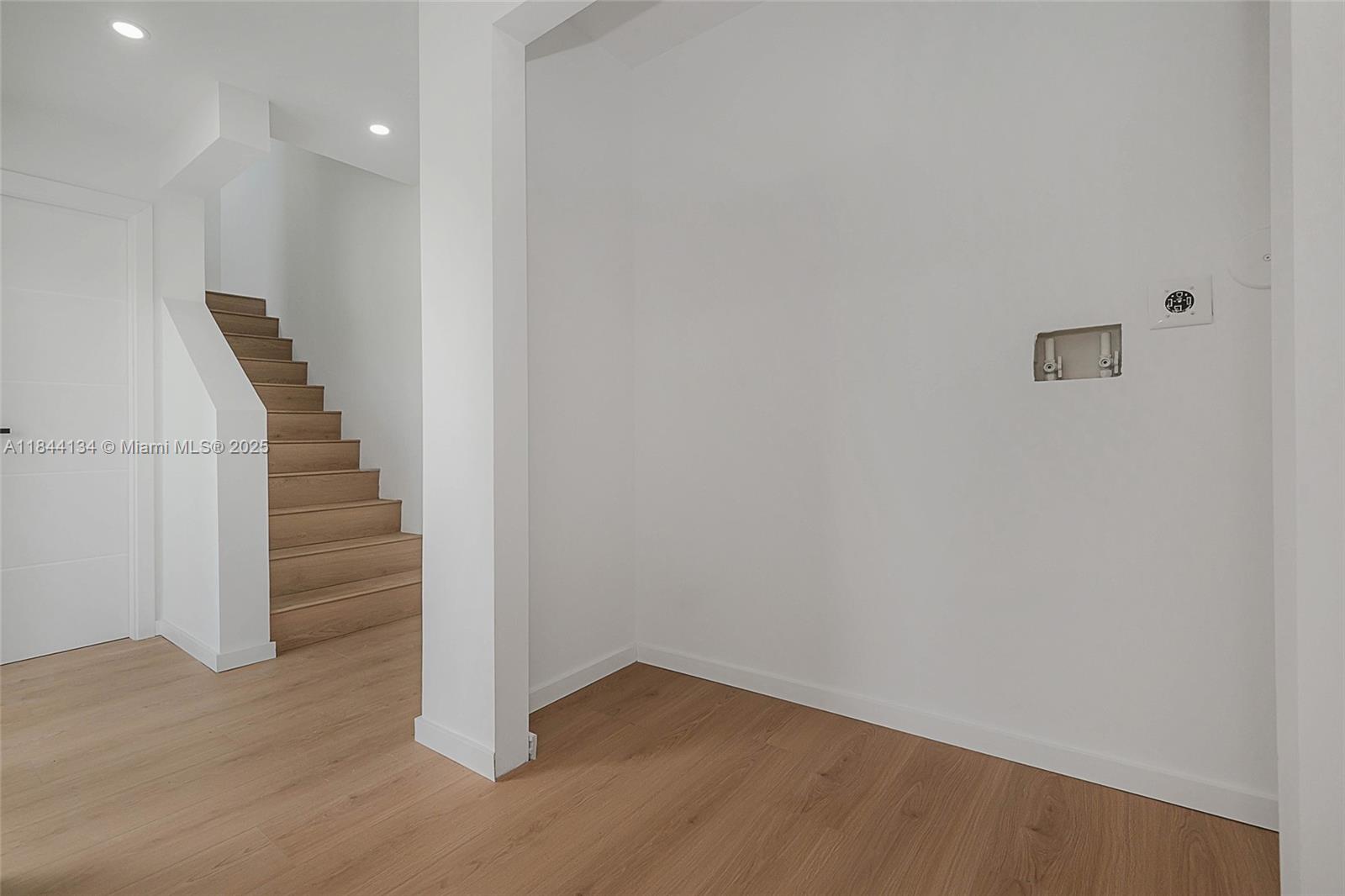 An open-concept living area features light wood flooring, white walls, recessed lighting, and a kitchen — 1975 Calais Dr # 1, Miami Beach FL 33141, MIAMI BEACH, FL