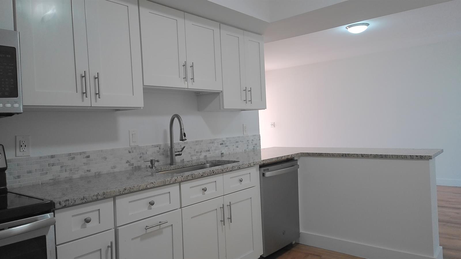 A kitchen with white cabinets, granite countertops, stainless steel appliances, and a tiled backsplash — 3180 Leewood Terrace # L108, Boca Raton FL 33431, BOCA RATON, FL