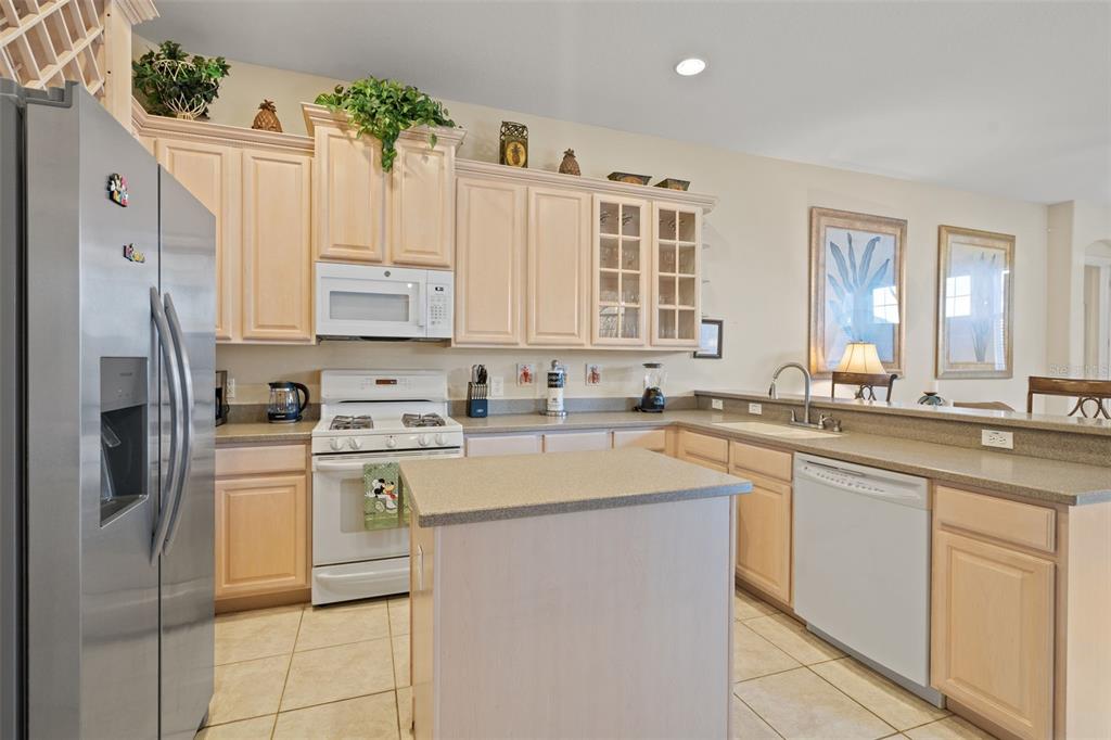 A kitchen with light wood cabinets, stainless steel appliances, a center island, and tile flooring — 7939 SEA PEARL CIRCLE, KISSIMMEE, FL