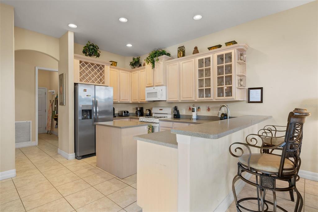 A kitchen features light-colored cabinetry, stainless steel appliances, a center island, and a breakfast bar — 7939 SEA PEARL CIRCLE, KISSIMMEE, FL