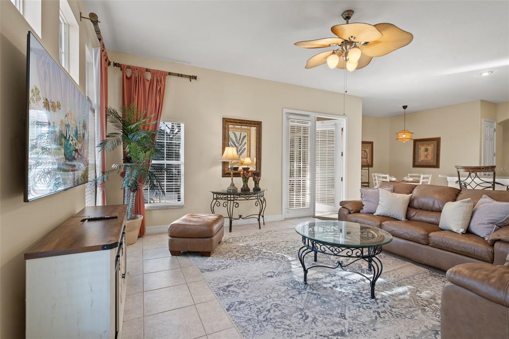 A living room features a brown leather sofa, tile floors, a ceiling fan, and television — 7939 SEA PEARL CIRCLE, KISSIMMEE, FL