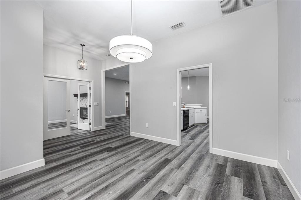 A dining room with gray wood-look flooring, a large pendant light, and two arched doorways — 2103 SW 75TH TERRACE, GAINESVILLE, FL