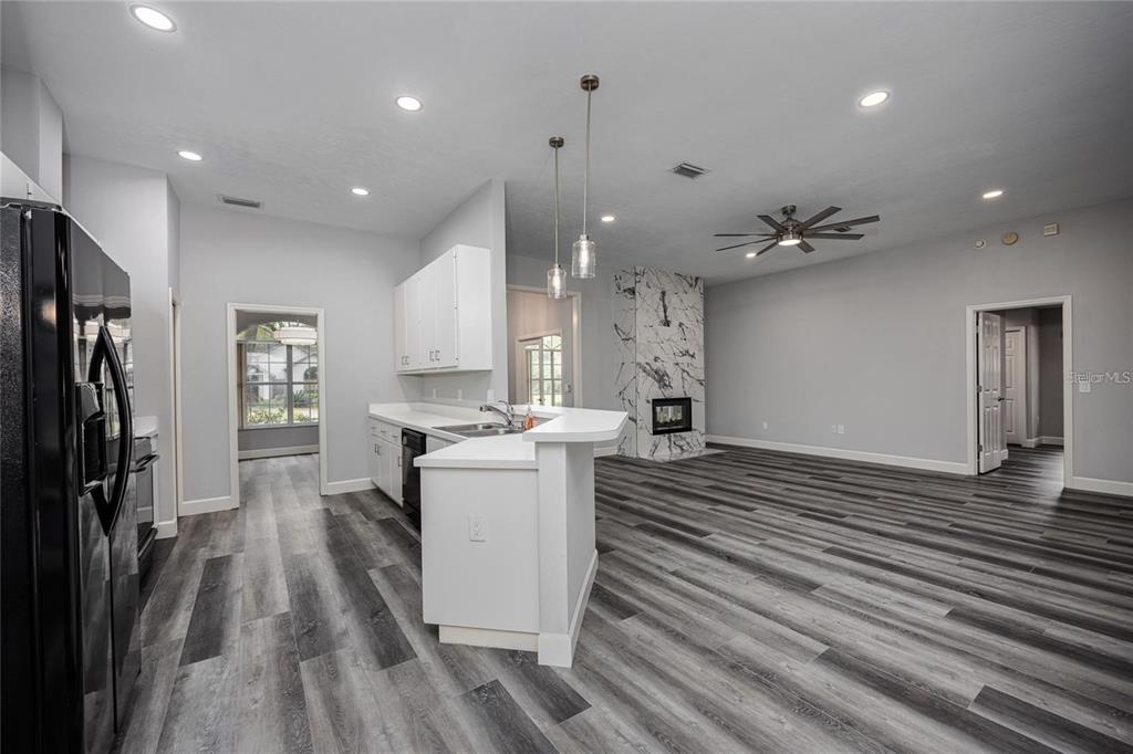 An open-concept kitchen and living area featuring white cabinets, a marble fireplace, and gray flooring — 2103 SW 75TH TERRACE, GAINESVILLE, FL