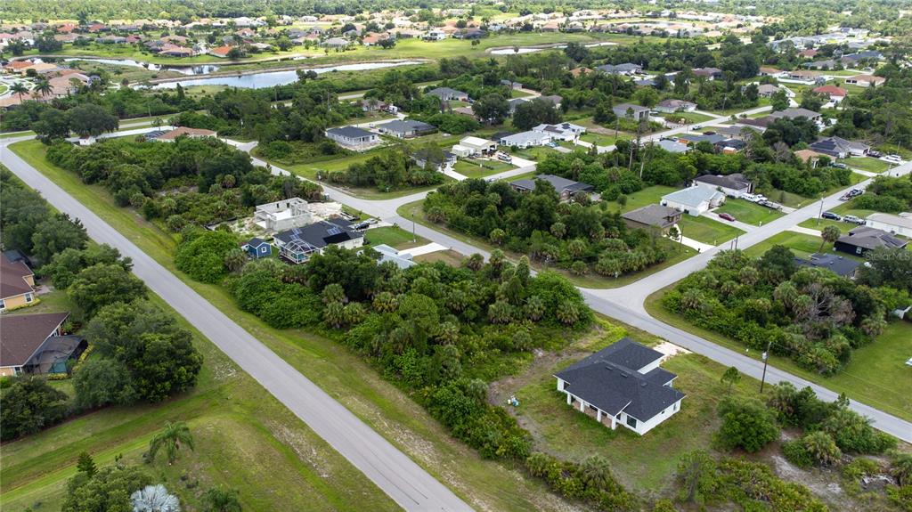 An aerial view shows a residential neighborhood with houses, paved roads, and dense green vegetation — ANDRIS STREET, NORTH PORT, FL