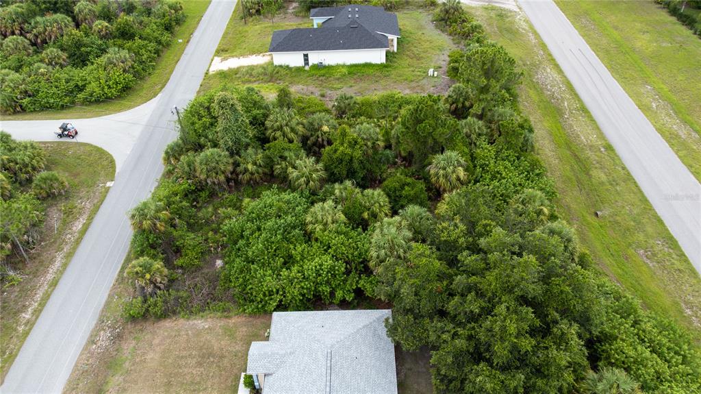 An aerial view shows a vacant, wooded lot situated between two paved roads and houses — ANDRIS STREET, NORTH PORT, FL