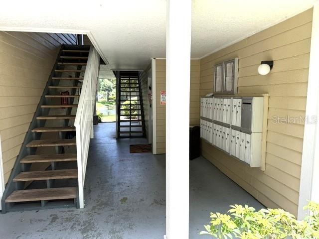 An outdoor covered walkway features a wooden staircase and a wall of metal mailboxes — 4211 CHATHAM OAK COURT UNIT 102, TAMPA, FL