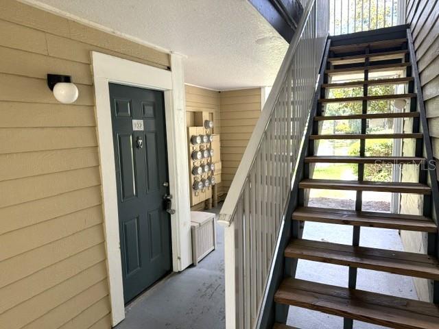 An exterior view shows a dark door labeled 102 next to a wooden staircase — 4211 CHATHAM OAK COURT UNIT 102, TAMPA, FL