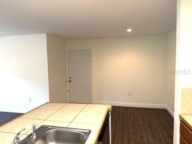 A kitchen island with a stainless steel sink faces a white door and wood-look flooring — 4211 CHATHAM OAK COURT UNIT 102, TAMPA, FL