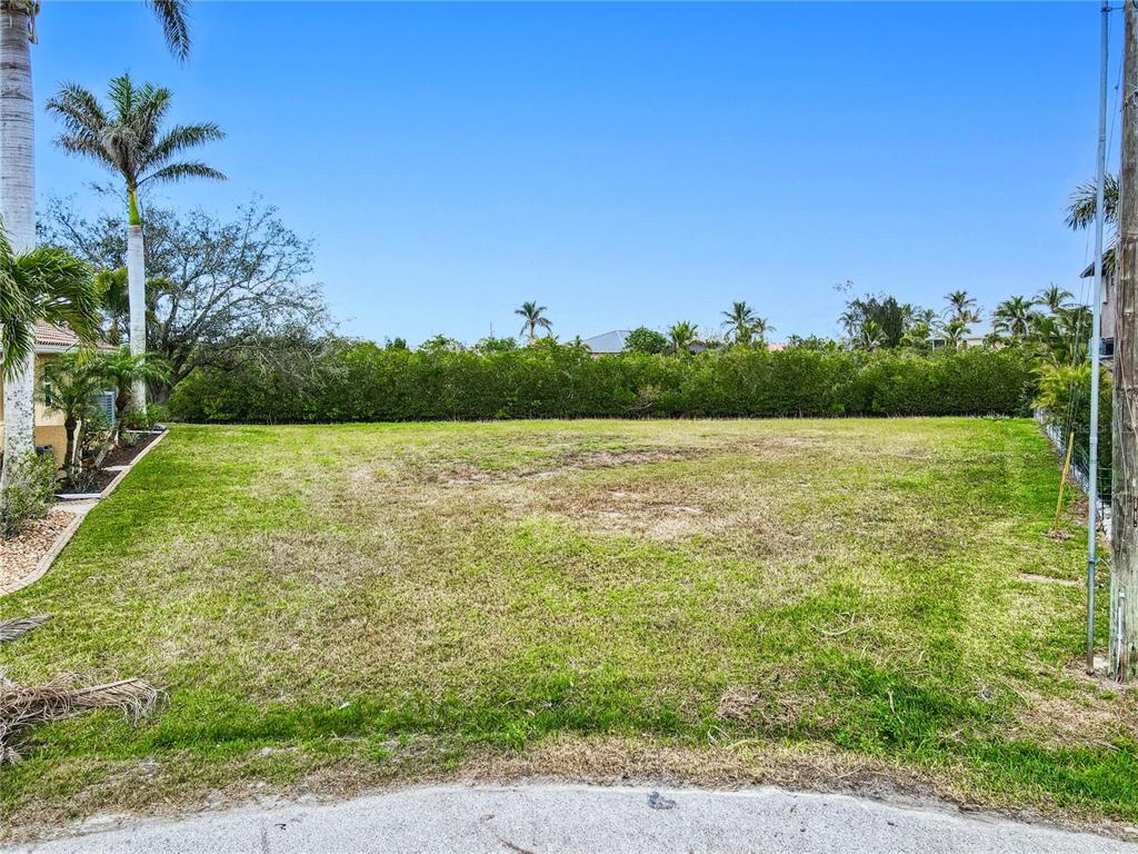 A vacant, grassy residential lot is bordered by a hedge and palm trees — 3500 MARSALA COURT, PUNTA GORDA, FL