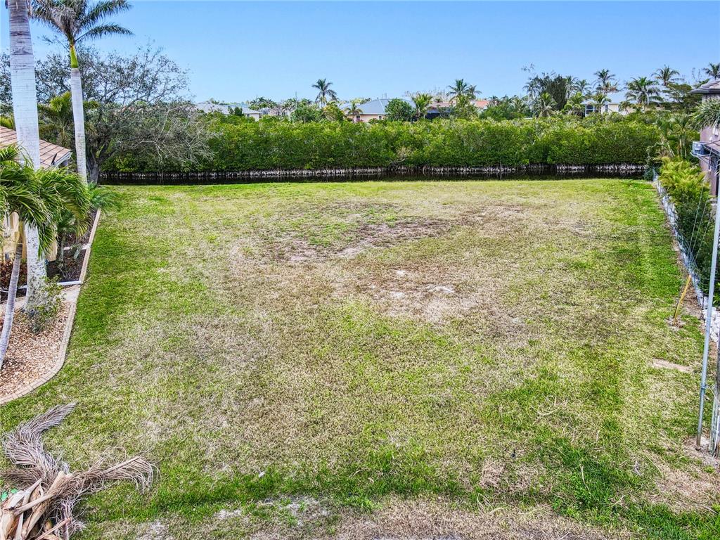 An elevated view shows a vacant, grassy residential lot bordered by a canal and trees — 3500 MARSALA COURT, PUNTA GORDA, FL