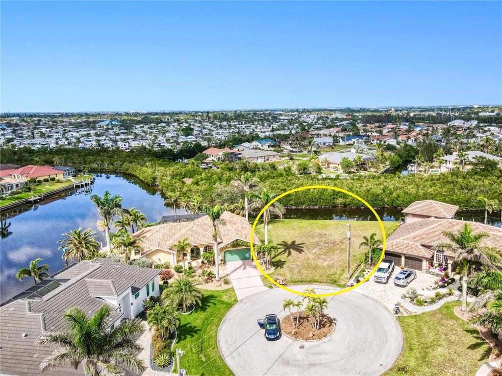 An aerial view shows a vacant residential lot situated between two houses near a canal — 3500 MARSALA COURT, PUNTA GORDA, FL