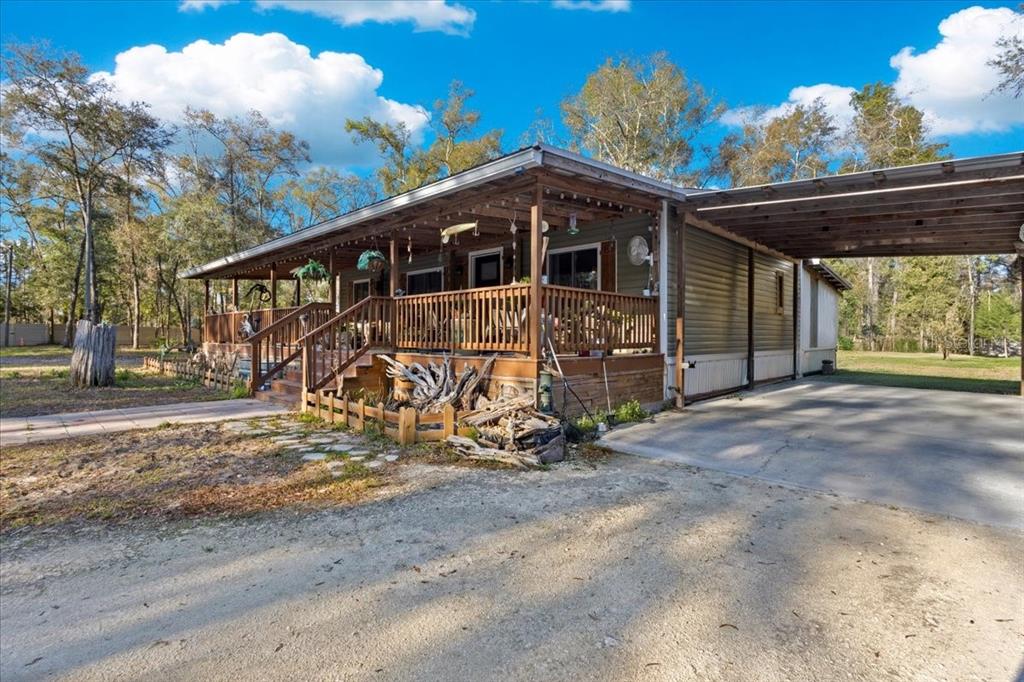 A single-story mobile home with a large wooden deck and an attached carport — 5850 NW 50TH STREET, BELL, FL