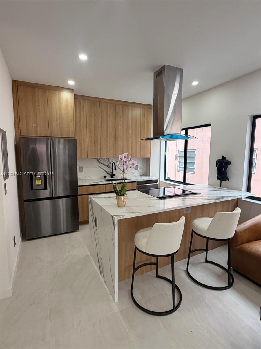 A modern kitchen features light wood cabinetry, white marble countertops, and a waterfall island — 2436 SW 7th St # 3, Miami FL 33135, MIAMI, FL