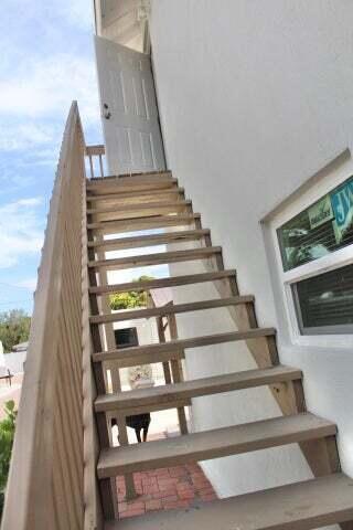An exterior wooden staircase leads up to an open white door on the building's side — 305 Cypress Drive # 1, Lake Park FL 33403, LAKE PARK, FL
