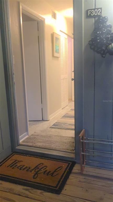 A view through an open doorway into a hallway with light flooring and white doors — 85 SE 16TH AVENUE UNIT F302, GAINESVILLE, FL