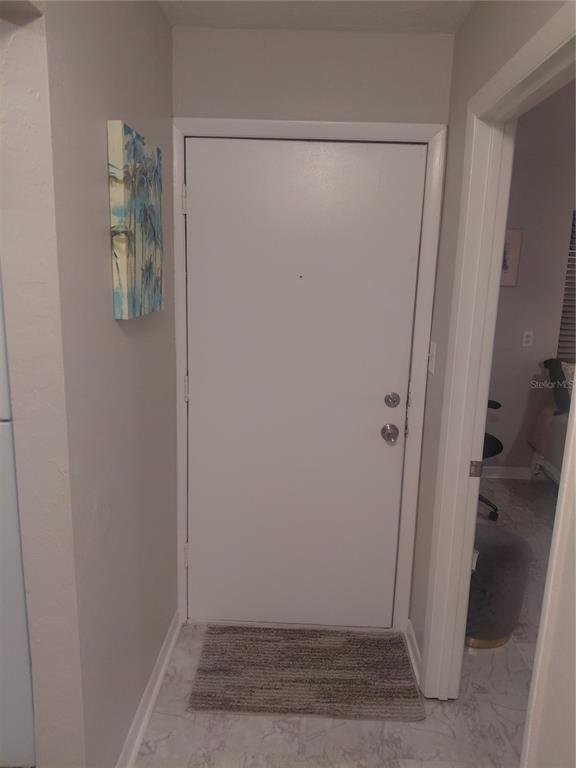 A white front door with a small rug sits in a neutral-toned entryway — 85 SE 16TH AVENUE UNIT F302, GAINESVILLE, FL
