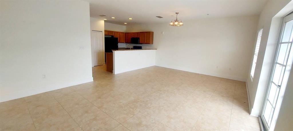 An open-concept living area features tile flooring, a kitchen with wooden cabinets, and a chandelier — 300 STATE STREET E UNIT 324, OLDSMAR, FL