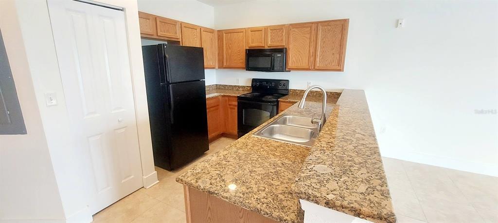 A kitchen features wood cabinets, granite countertops, black appliances, and a double-basin sink — 300 STATE STREET E UNIT 324, OLDSMAR, FL