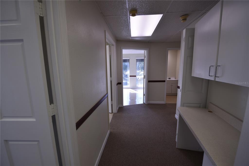 A hallway with carpeted floors, white walls, a built-in desk, and several doorways — 1200 N CENTRAL AVENUE UNIT 212, KISSIMMEE, FL