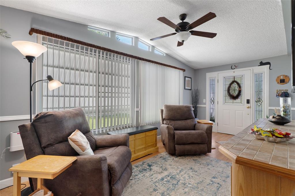 A living room features two brown recliners, a ceiling fan, and a front entry door — 7436 NIELSON AVENUE, BROOKSVILLE, FL