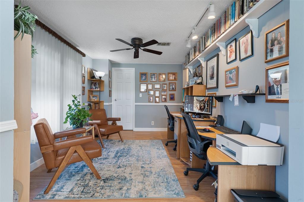 A home office features two desks, two leather chairs, a rug, and wall-mounted bookshelves — 7436 NIELSON AVENUE, BROOKSVILLE, FL