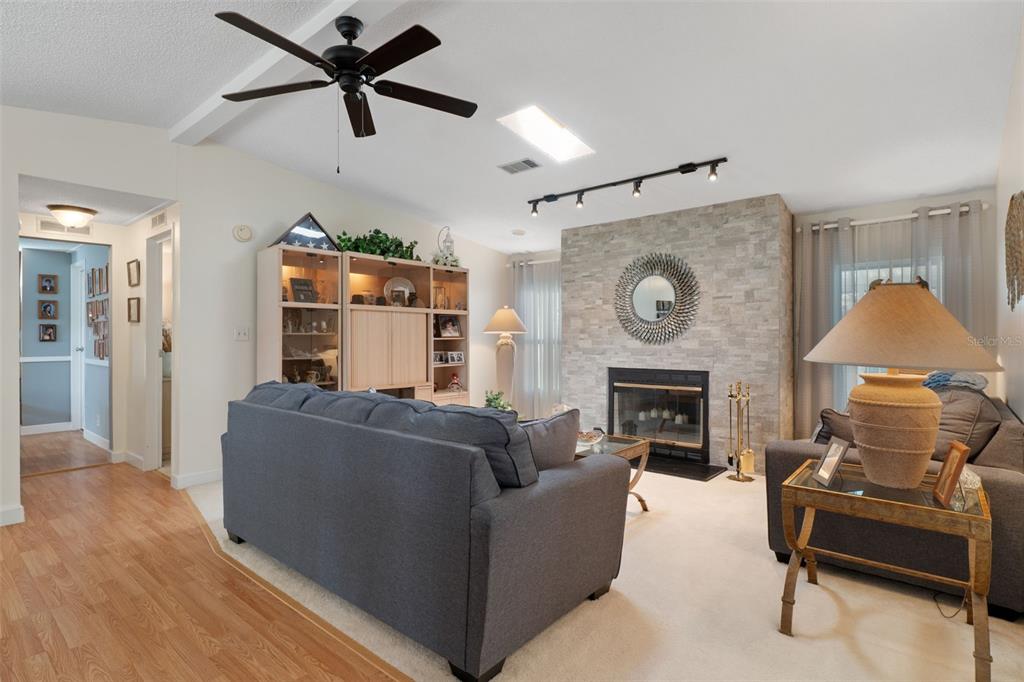 A living room features a stone fireplace, a dark sofa, and a ceiling fan — 7436 NIELSON AVENUE, BROOKSVILLE, FL