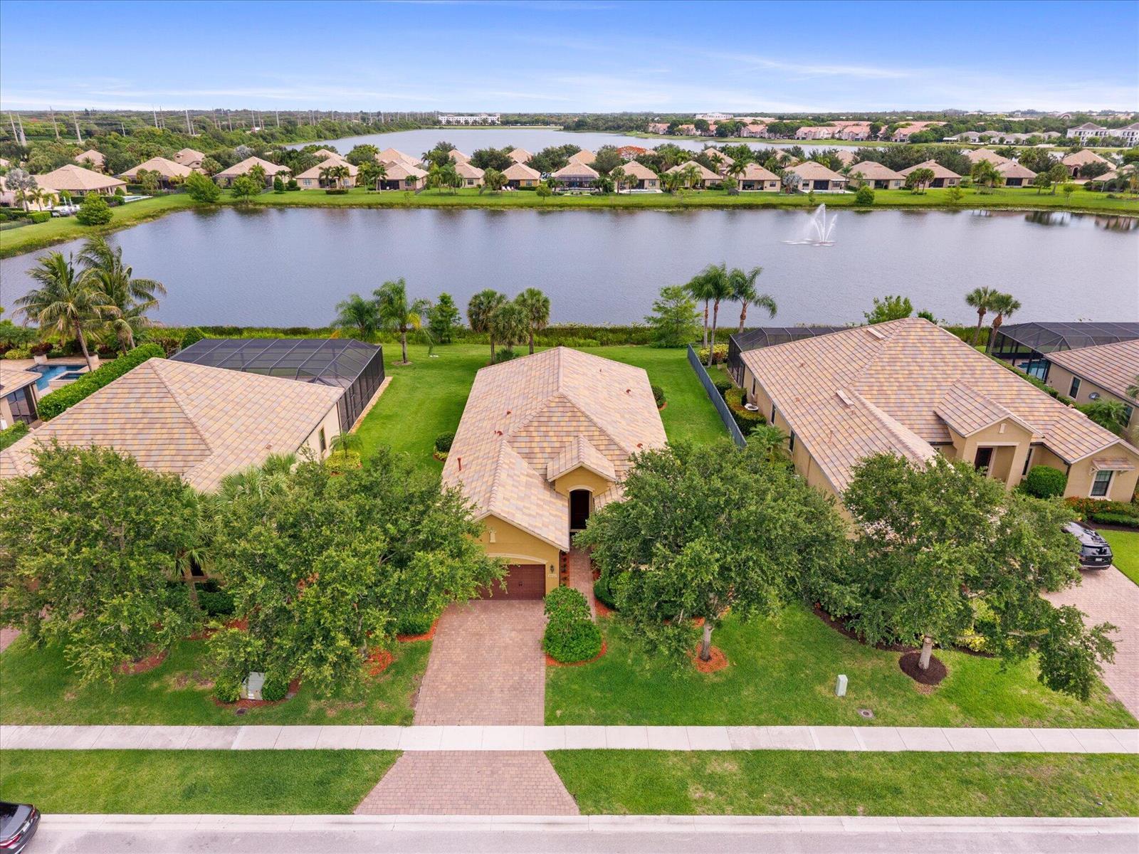 An aerial view shows a suburban house with a tile roof situated by a lake — 4452 Siena Circle, Wellington FL 33414, WELLINGTON, FL